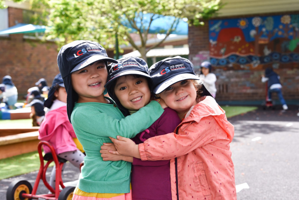 Happy, smiling children in hats hug in the playground