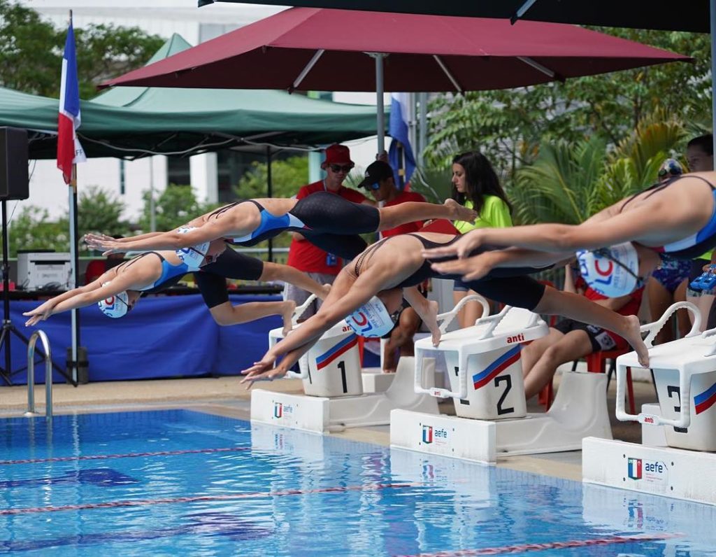 International French School of Sydney swimmers diving into pool at swimming competition