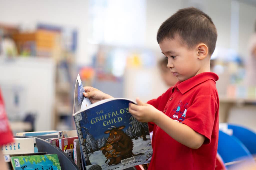 Child reading book in library at LCS